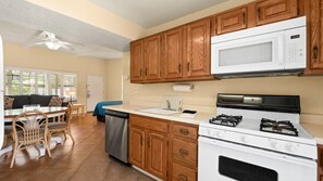 A compact kitchen with wooden cabinets, a microwave, a stove, and a dishwasher. - Palm Springs Bliss in a Studio Retreat (Palm Springs)