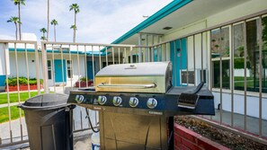 An outdoor grill with a built-in chimney, a trash can, and a view of a building with a blue and white facade. - Palm Springs Bliss in a Studio Retreat (Palm Springs)