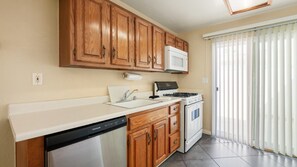 A kitchen with wooden cabinets, a white countertop, a built-in microwave, a stove, and a dishwasher. - Palm Springs Bliss in a Studio Retreat (Palm Springs)