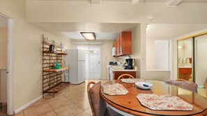 A compact kitchen with a dining area, featuring a refrigerator, cabinets, and a coffee maker. - Desert Charm & Fireside Comfort (Palm Springs)