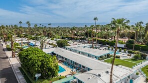 A hotel with a rooftop pool, multiple guest rooms, and a view of palm trees and mountains. - Fireside Palm Springs Escape | 1BR + 2 Baths (Palm Springs)