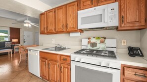 A kitchen with wooden cabinets, a microwave, a stove, and a sink. - Fireside Palm Springs Escape | 1BR + 2 Baths (Palm Springs)