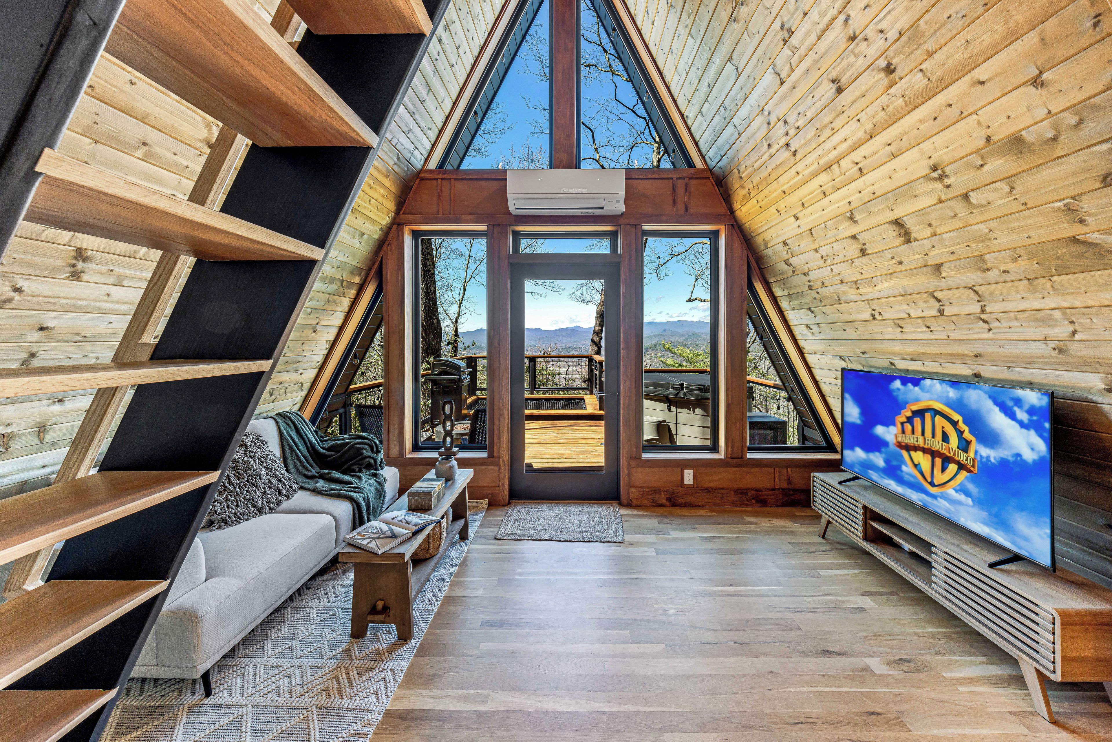 A cozy interior with a sofa, TV, and wooden beams.