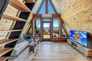A cozy interior with a sofa, TV, and wooden beams.