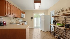 A kitchen with wooden cabinets, a microwave, a stove, a refrigerator, and a coffee maker. - Palm Springs Easy Livin’ Suite | 1BR + Pool (Palm Springs)