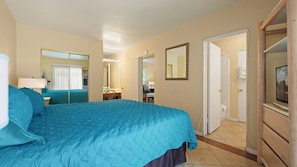A hotel room with a large bed, a mirror, a television, and a bathroom visible through an open door. - Palm Springs Easy Livin’ Suite | 1BR + Pool (Palm Springs)