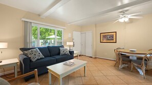 A living room with a sofa, coffee table, dining table, chairs, and a ceiling fan. - Palm Springs Easy Livin’ Suite | 1BR + Pool (Palm Springs)