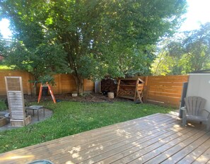 A backyard with a wooden deck, a tree, a shed, and a chair. - Renovated Suite - Downtown Fernie - Pet Friendly (Fernie)