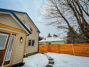 A residential house with a wooden fence, a snow-covered yard, and a clear sky. - Renovated Suite - Downtown Fernie - Pet Friendly (Fernie)