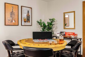 A round wooden table with a poker set, a bottle of whiskey, and a Scrabble box. - BourbonTrl Luxe-15acres-GolfSim-HotTub-GameRm (Versailles)
