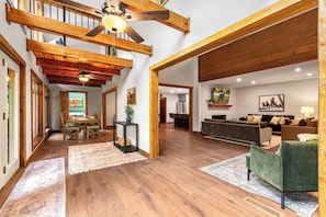 A spacious living area with wooden beams, a dining table, and a sofa. - BourbonTrl Luxe-15acres-GolfSim-HotTub-GameRm (Versailles)