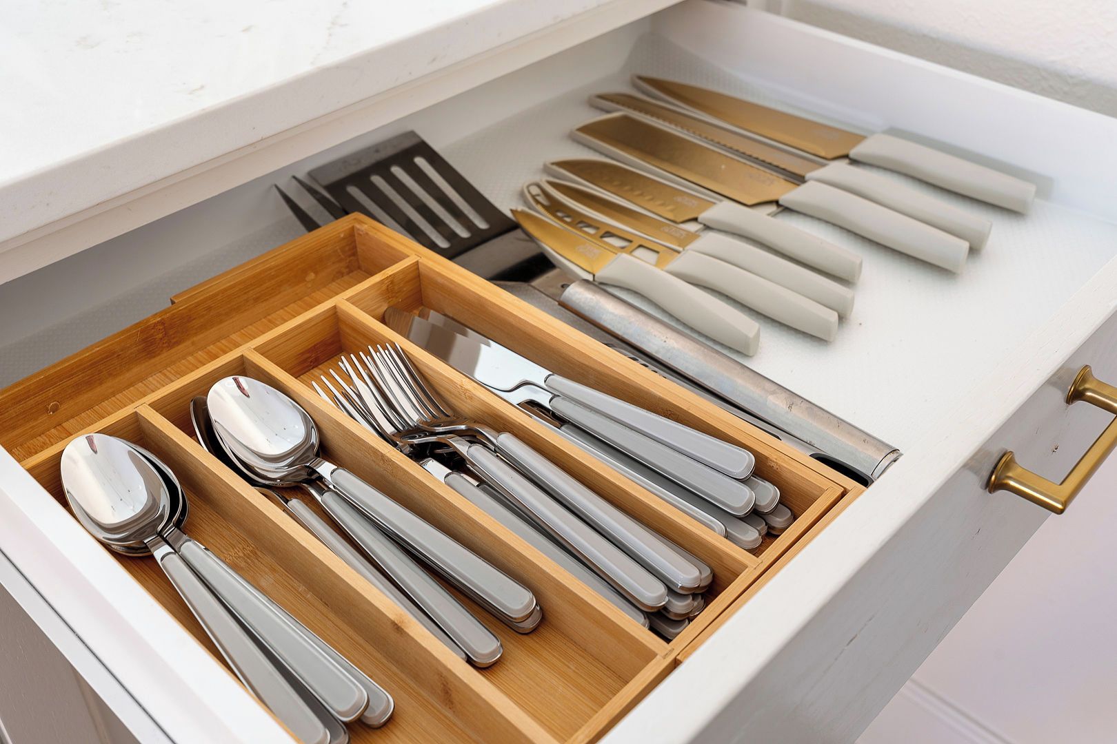 A drawer with utensils including spoons, forks, and knives.