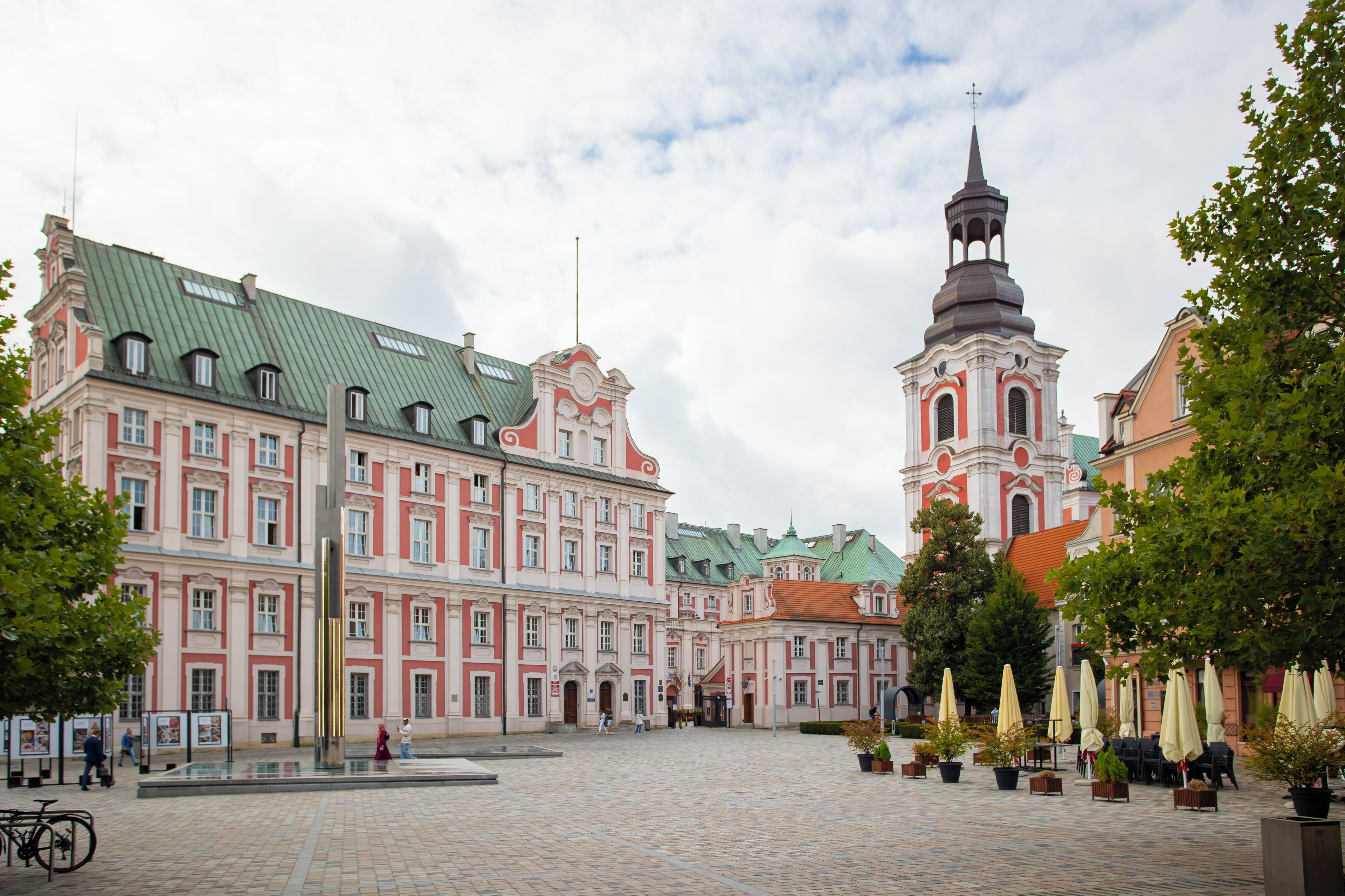A historic building with a prominent tower and a courtyard with outdoor seating.