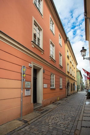 A cobblestone street with a building featuring a large door and multiple windows. - Studio z Antresolą 1 min od Rynku (Poznań)