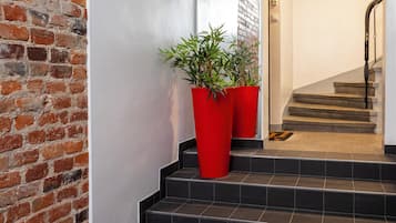 Una escalera con baldosas negras y una alfombra roja que conduce a una puerta con un cartel.