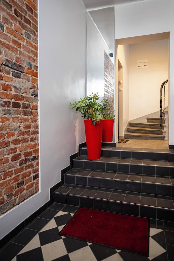 A staircase with black tiles and a red carpet leading to a door with a sign. - Studio z Antresolą 1 min od Rynku (Poznań)