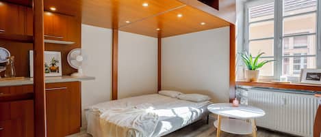 A bedroom with a bed, bedside table, and a window with a view.