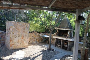 Eine Terrass mit Steinsäule, Grill und Tisch.