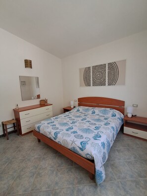 Ein Schlafzimmer mit einem Bett, Nachttischen, einer Kommode, einem Spiegel und einem Wandbild.