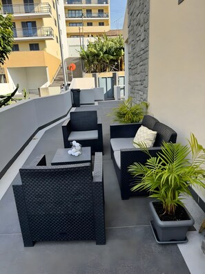 A rooftop patio with outdoor furniture, potted plants, and a view of surrounding buildings. - Apartment 'Alforra Residence 1' with Mountain View, Wi-Fi and Air Conditioning (Câmara de Lobos)