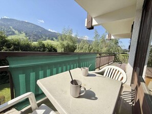 A balcony with a table and chairs, two mugs, and a view of a mountainous landscape. - Ground floor, balcony, tv, ski locker, 67m², Praz sur Arly (Praz-sur-Arly)