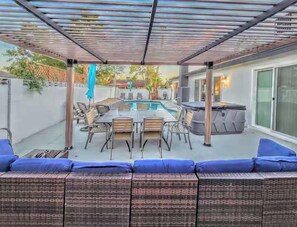 Eine Außenpatio mit Pool, Esstisch und Sitzgelegenheit.