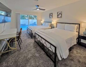 Ein Schlafzimmer mit einem großen Bett, einem Schreibtisch und einem Stuhl. Ein Fenster bietet einen Blick ins Freie.