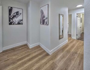 A hallway with wooden flooring, white walls, and framed artwork. - Vegas Group Getaway | Private Pool & Grill (Las Vegas)