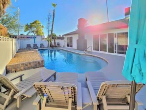 A swimming pool with lounge chairs, a covered area, and a building with a sign in the background. - Vegas Group Getaway | Private Pool & Grill (Las Vegas)