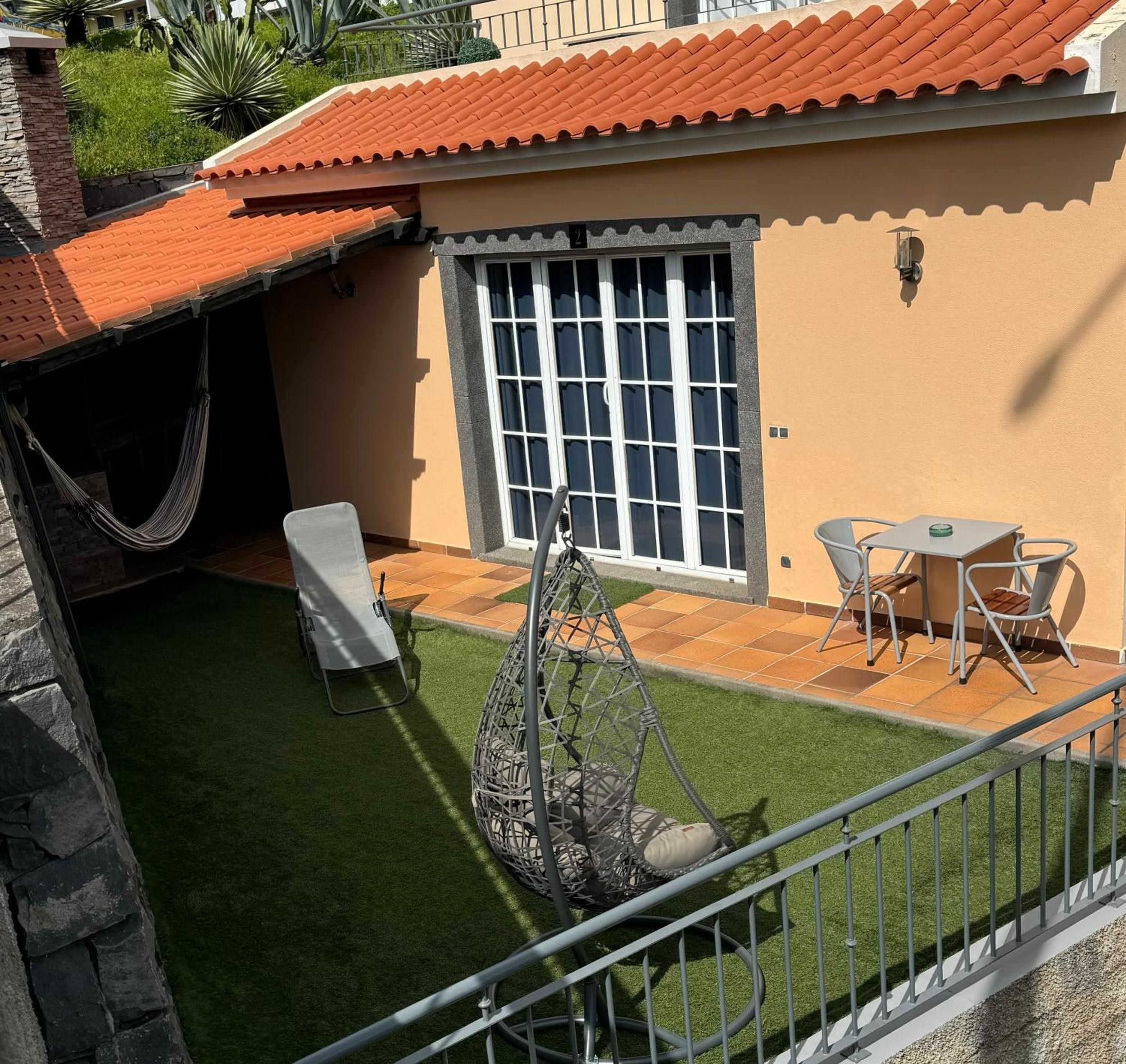 Eine Terrasse mit Hängematte, Schaukel und Tisch mit Stühlen.