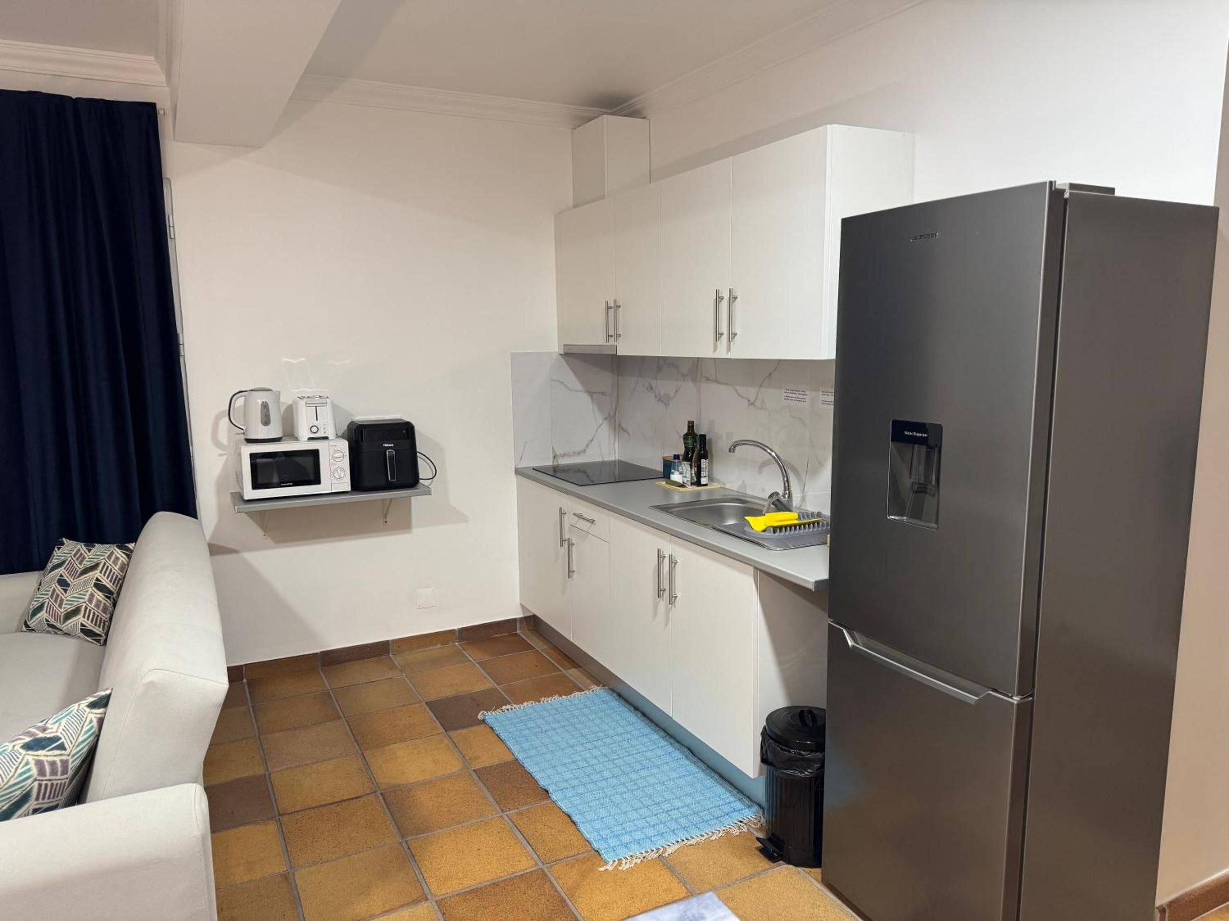 A compact kitchenette with a refrigerator, microwave, toaster, and sink.