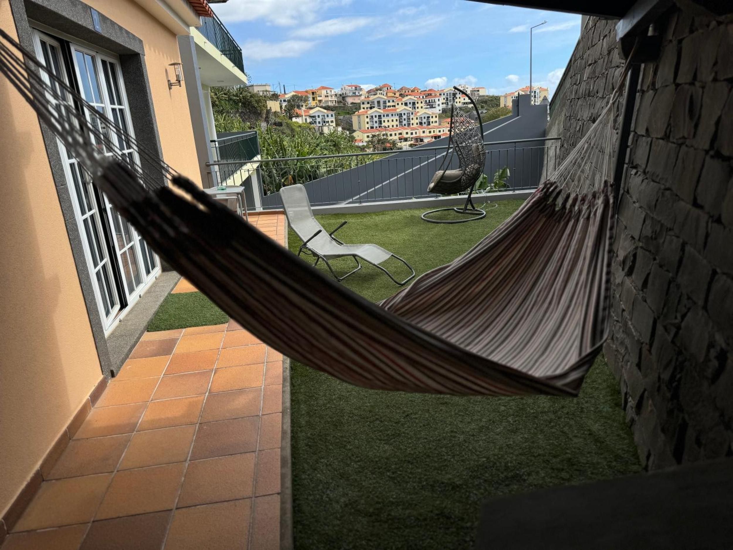 Una hamaca en un balcón con vistas a un barrio residencial.