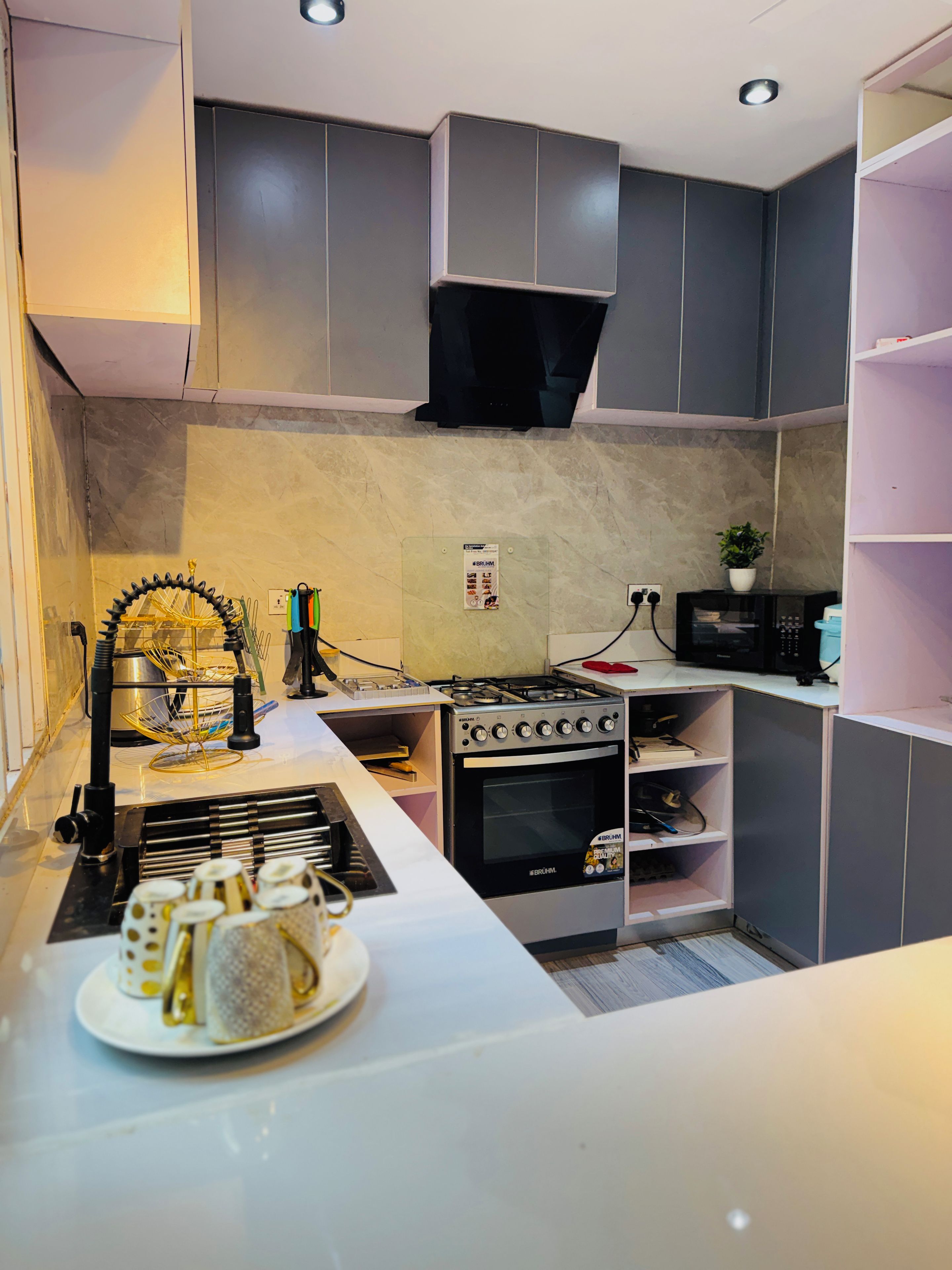 A modern kitchen with grey cabinetry, a built-in stove, and a small island with a plate of food.