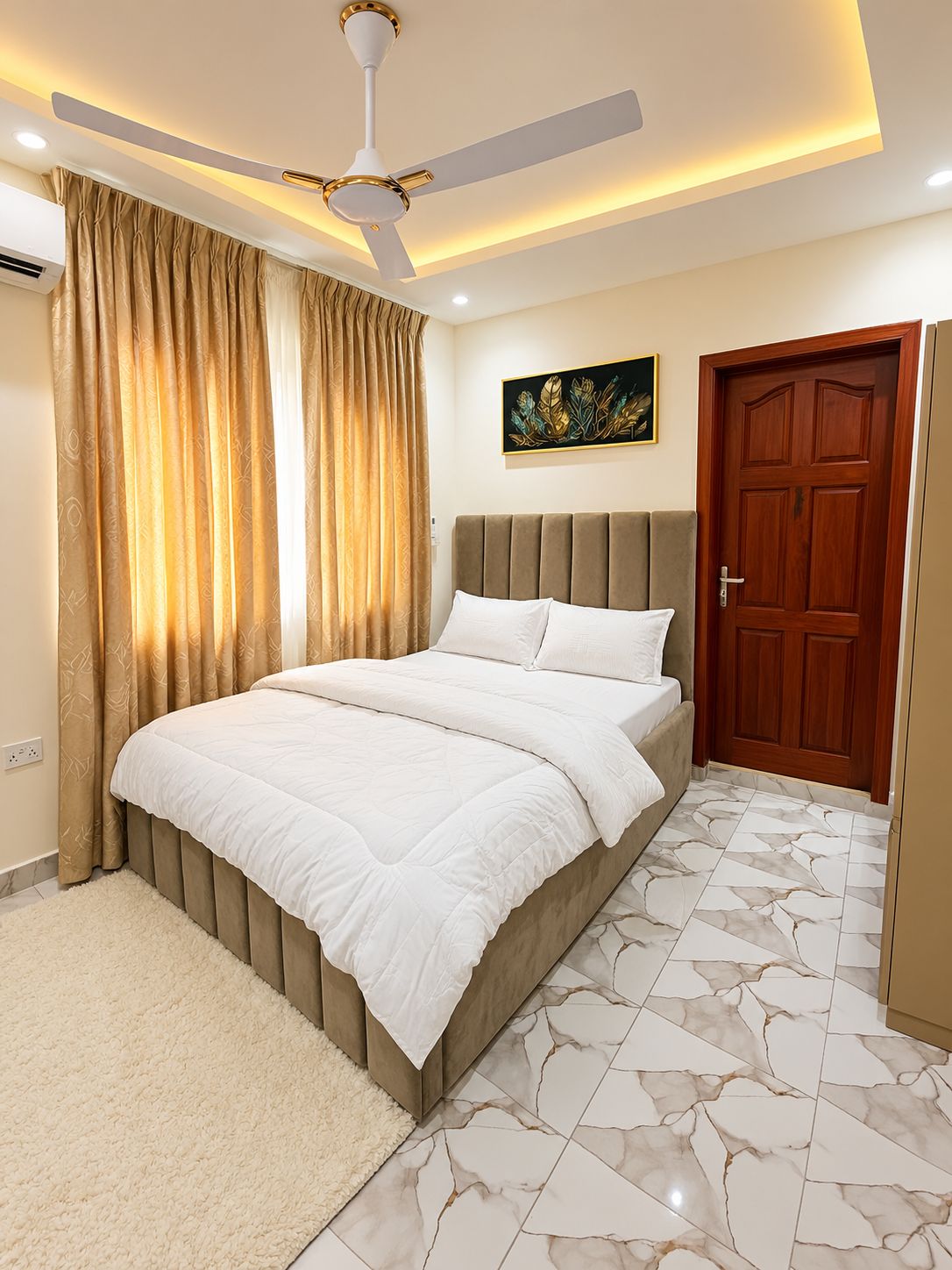 Ein Schlafzimmer mit Bett, Vorhängen, Deckenventilator, einer Tür und einem Wandbild.