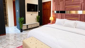 Ein modernes Schlafzimmer mit einem großen Bett, einem Deckenventilator, einem Flachbildfernseher und einem Marmorboden.