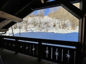 A covered outdoor area with a snow-covered landscape visible through a railing with decorative elements. - 3rd floor, balcony, tv, ski locker, 28m², Praz sur Arly (Praz-sur-Arly)