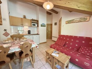 Ein gemütliches Wohnzimmer mit einem roten Sofa, einem Holzesstisch und Stühlen.