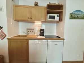 A compact kitchen with wooden cabinets, a microwave, a coffee maker, and a dishwasher. - 3rd floor, balcony, tv, ski locker, 28m², Praz sur Arly (Praz-sur-Arly)