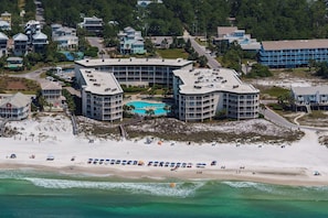 A beachfront hotel with multiple buildings, a swimming pool, and a sandy beach with umbrellas. - Gulf View Ocean Front Condo, Balconies, 2 Pools, Hot tub, Sauna, Gym, Full Kitchen, Washer and Dryer (Santa Rosa Beach)