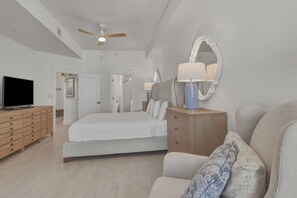 A modern bedroom with a large bed, a TV, wooden furniture, and a ceiling fan. - Gulf View Ocean Front Condo, Balconies, 2 Pools, Hot tub, Sauna, Gym, Full Kitchen, Washer and Dryer (Santa Rosa Beach)