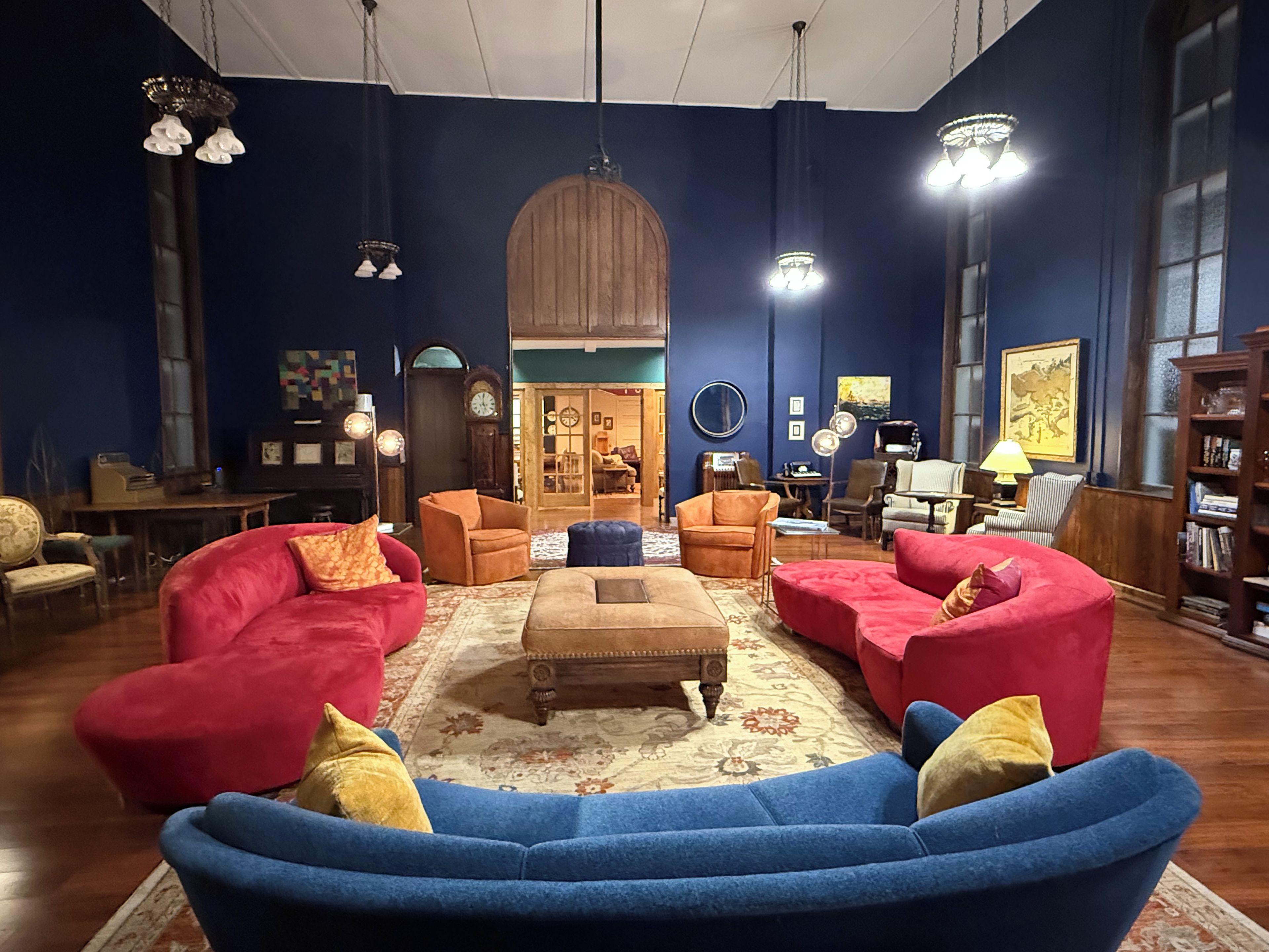 Una sala de estar acogedora con un sofá azul, sillones rojos y una mesa de centro de madera.