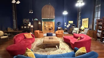 Una sala de estar acogedora con un sofá azul, sillones rojos y una mesa de centro de madera.