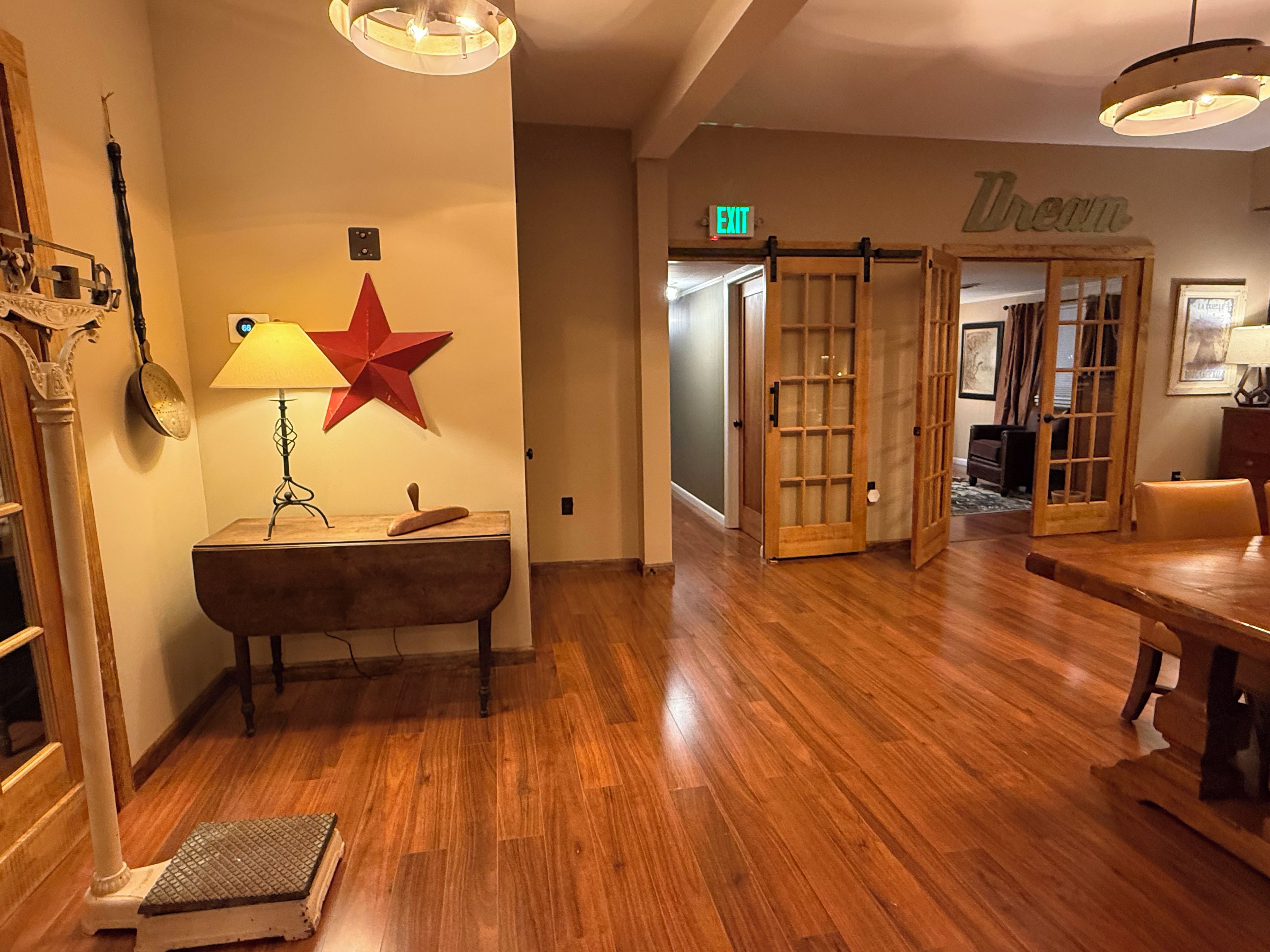 Una habitación con piso de madera, una lámpara, una decoración con una estrella roja y una puerta que dice 'EXIT'.