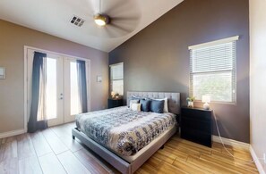 A bedroom with a bed, a ceiling fan, a window, and a nightstand. - Desert Retreat | Pool, Near Spring Training (Surprise)