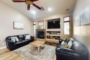 Ein Wohnzimmer mit Kamin, Fernseher und zwei Ledersofas.