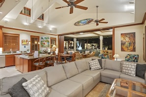 A spacious living area with a large sofa, dining table, and chairs, a ceiling fan, and artwork on the walls. - Waikoloa, Kolea, Spacious 6 BR, Sleeps 16 (Waikoloa Village)