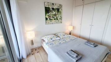 Une chambre à coucher comprenant un lit, deux lampes de chevet, un tableau décoratif et une armoire.
