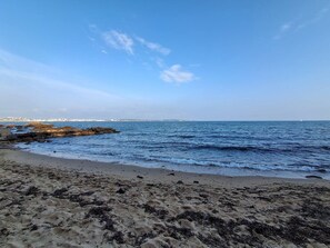 Una spiaggia con cielo sereno, acqua calma e costa in lontananza.