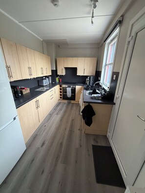 Eine kleine Küche mit Holzausstattung, einer schwarzen Arbeitsplatte und einem eingebauten Backofen.