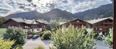 A hotel with multiple wooden buildings, a parking lot, and mountains in the background.